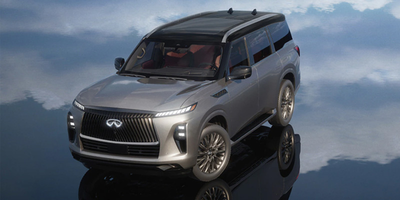 A silver 2025 INFINITI QX80 SUV with a black roof parked on a reflective surface, showcasing its sleek design.