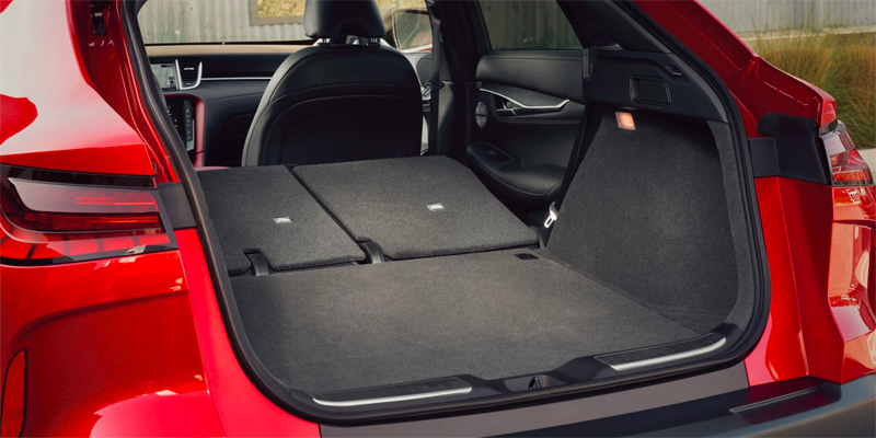 A spacious red 2025 INFINITI QX55 SUV trunk with folded back seats and a flat cargo area.